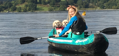 Image of Kelsy on a boat with her dog on a river